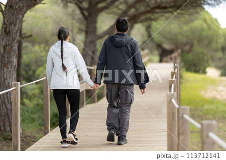 A man and woman are walking on a wooden bridge 113712141