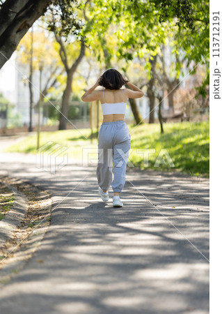 A woman is walking down a path in a park A woman is walking down a path in a park 113712191