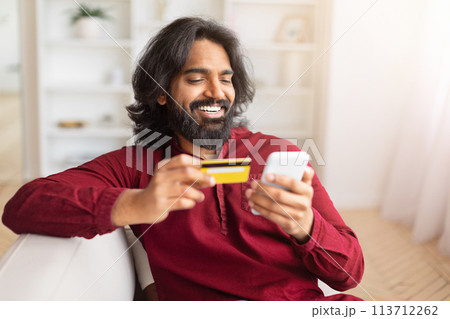 Happy man shopping online with card at home Happy man shopping online with card at home 113712262