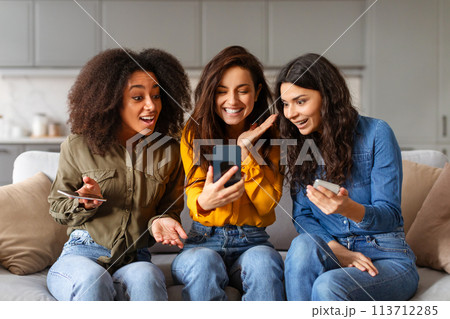 Three women reacting to content on smartphone 113712285