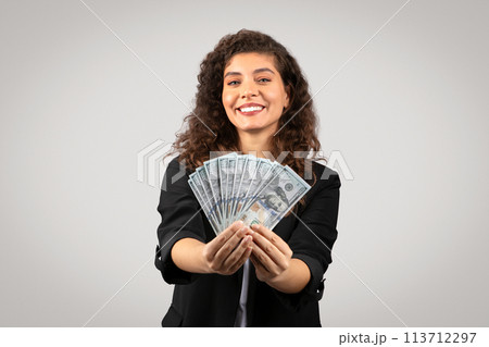 Woman holding a fan of US dollar bills 113712297