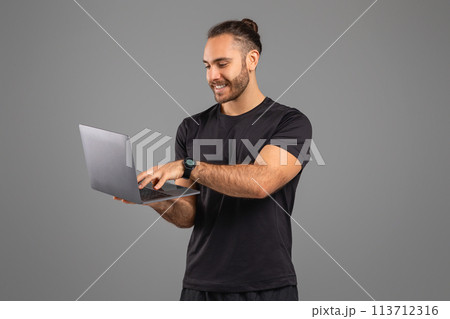 Man using laptop and smiling on grey background 113712316
