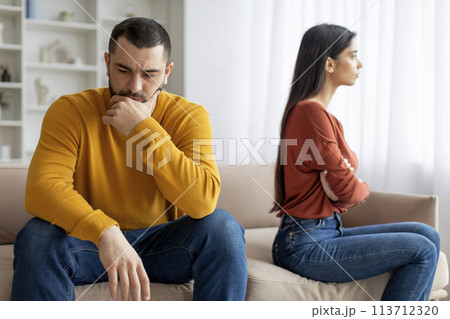 Man and woman sitting apart looking upset 113712320