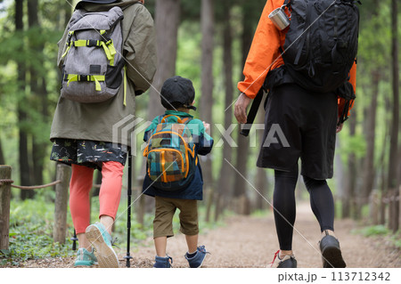 ハイキングする親子　緑の中登山やトレッキングする家族　夏のレジャーやアウトドアのお出かけのイメージ　 113712342