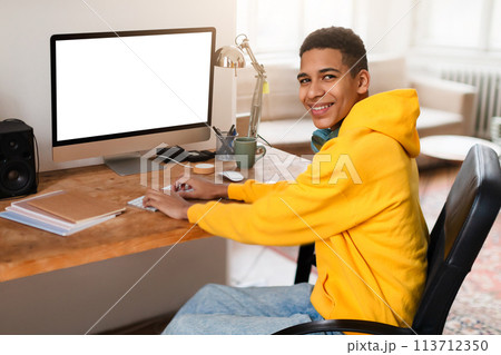 Young man with headphones at computer workstation 113712350