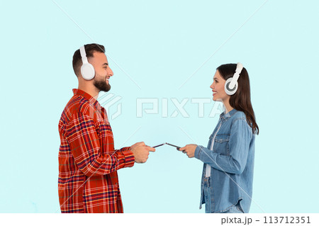 Man and woman using smartphones and headphones Man and woman using smartphones and headphones 113712351