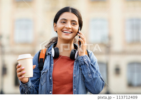 Indian student talking on phone with coffee Indian student talking on phone with coffee 113712409