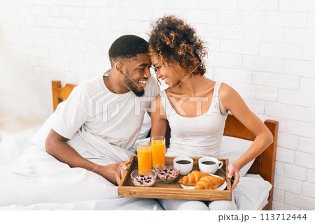 Happy black couple enjoying breakfast in bed Happy black couple enjoying breakfast in bed 113712444