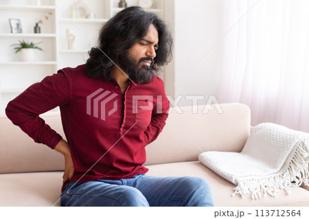 Man with back pain on a modern sofa 113712564