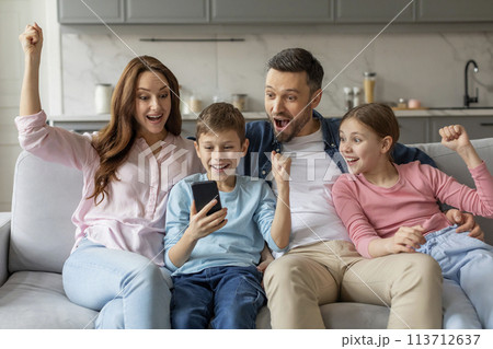 Family celebrating success with smartphone at home 113712637
