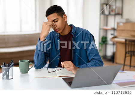 Focused man working on laptop at home desk Focused man working on laptop at home desk 113712639