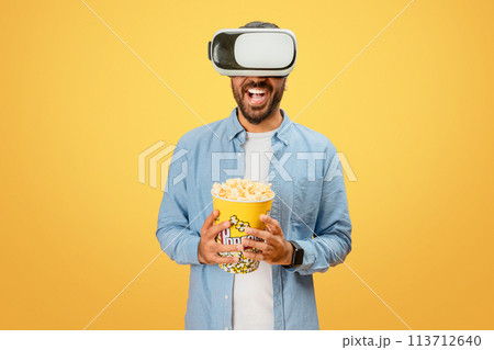 VR user with popcorn delighted by virtual world 113712640