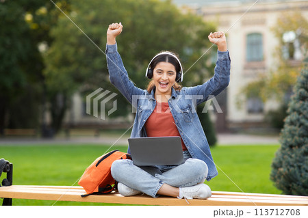 Excited woman student with laptop celebrating success 113712708