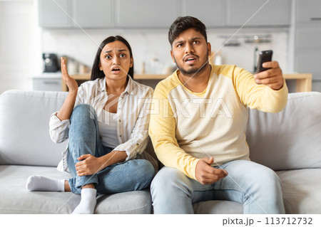 Shocked Indian Couple Reacting to News in Bright Living Room Shocked Indian Couple Reacting to News in Bright Living Room 113712732