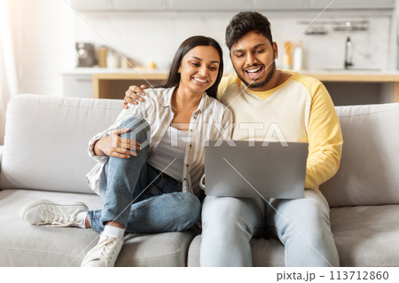 Loving Indian couple relaxing with laptop home Loving Indian couple relaxing with laptop home 113712860