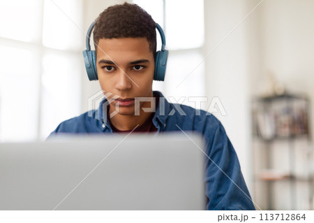 Young man with headphones using laptop 113712864