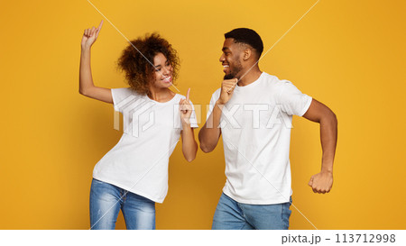 Positive black guy and girl dancing on orange background Positive black guy and girl dancing on orange background 113712998