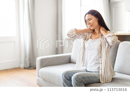 Woman with neck pain at home, copy space 113713018