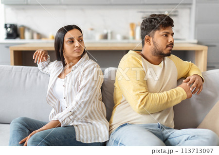 Indian Couple Expressing Discontent While Sitting on Couch Indoors Indian Couple Expressing Discontent While Sitting on Couch Indoors 113713097