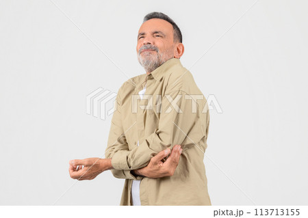 Senior man rubbing his elbow against studio background 113713155