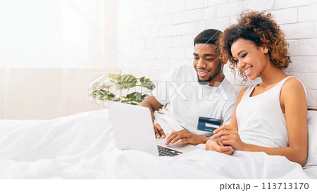 Smiling couple using laptop in bed at home 113713170