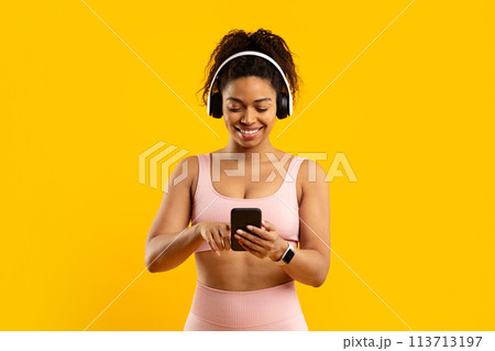 Smiling african american woman with phone and headphones 113713197
