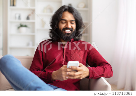 Man contently texting on smartphone at home 113713365