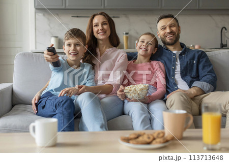 Family watching TV together, smiling joyfully at home 113713648
