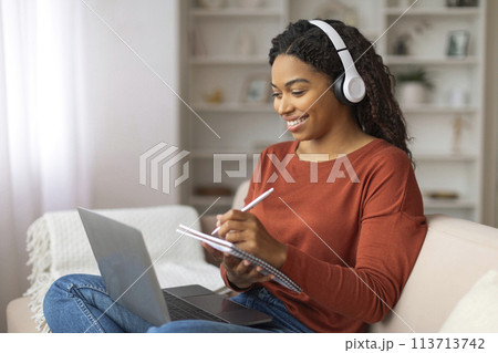 Black Woman Sitting on Couch With Laptop and Headphones 113713742