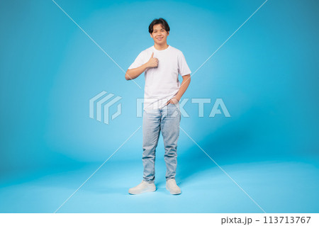 Teen standing in white shirt giving thumbs up 113713767
