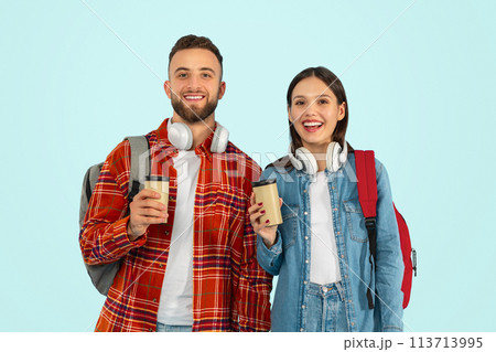 couple students posing with backpacks and takeaway coffee, blue background 113713995