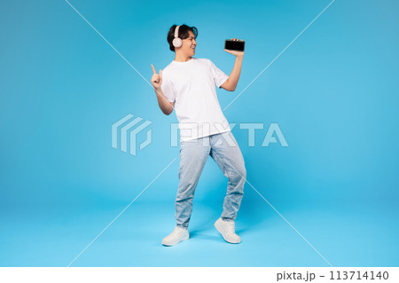 Guy dancing with smartphone on blue background 113714140
