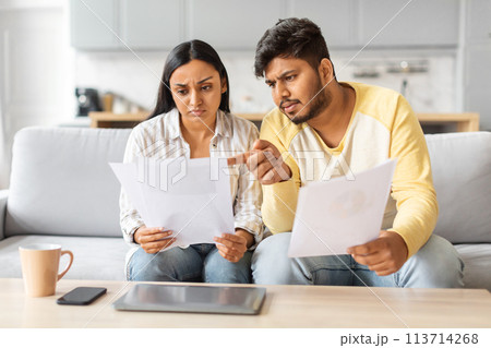 Indian Man and Woman Reviewing Papers on Couch 113714268