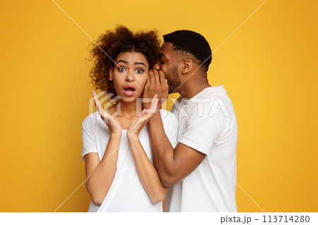 African american man whispering to shocked girlfriend 113714280