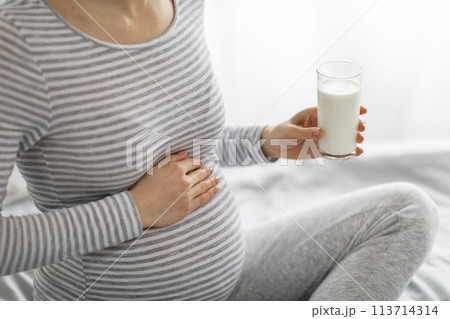 Pregnant woman holding a glass of milk 113714314