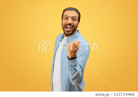 Excited man with raised fist exuding happiness 113714460