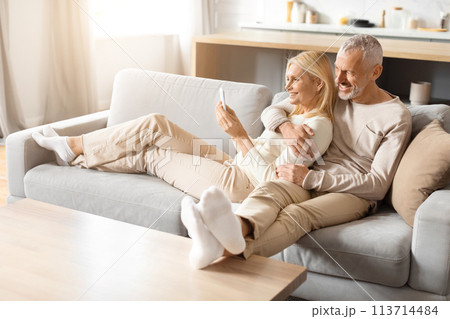 Couple relaxing on a minimalist couch in a bright room 113714484