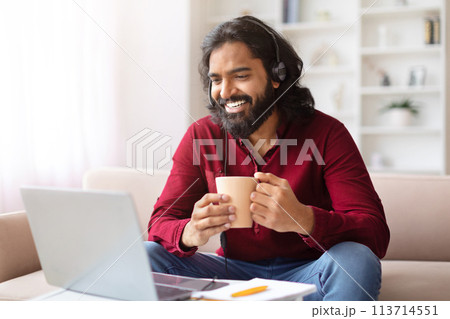 Man with mug enjoying work on laptop 113714551