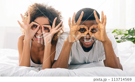 Cheerful happy couple in love holding fingers near eyes 113714569