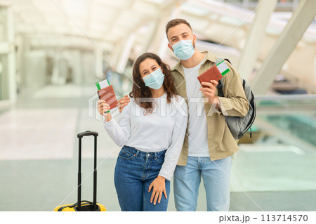 Happy Couple In Medical Masks Posing In Airport With Passports And Tickets Happy Couple In Medical Masks Posing In Airport With Passports And Tickets 113714570