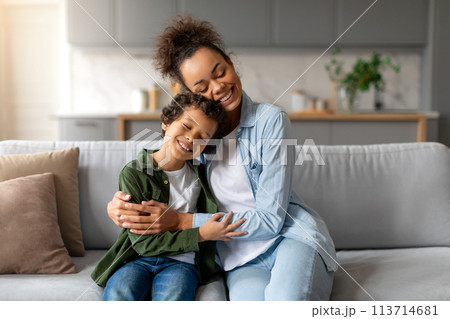 Mother and son enjoying a cuddle on couch 113714681