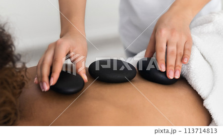 Woman having hot stone massage on back Woman having hot stone massage on back 113714813