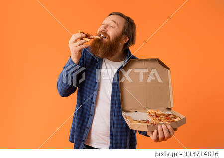 Caucasian redhaired bearded man biting pizza slice with appetite, studio Caucasian redhaired bearded man biting pizza slice with appetite, studio 113714816