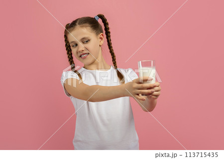 Contemplative girl looking at glass of milk Contemplative girl looking at glass of milk 113715435