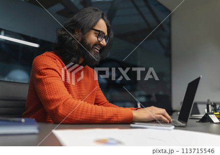 Joyful man typing on a laptop in the office 113715546