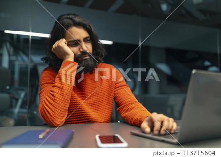 Man bored at work on laptop 113715604