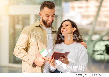 Excited couple checking their passports and boarding passes in airport terminal 113715609