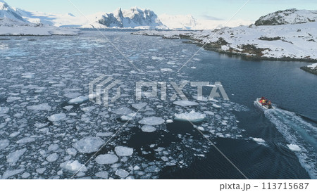 Zodiac Boat in Antarctica Ocean Aerial tracking. Drone Flight Overview of Antarctic South Pole. Rubber Boat Float in Frozen Winter Water Landscape Among Ice Shore. 113715687