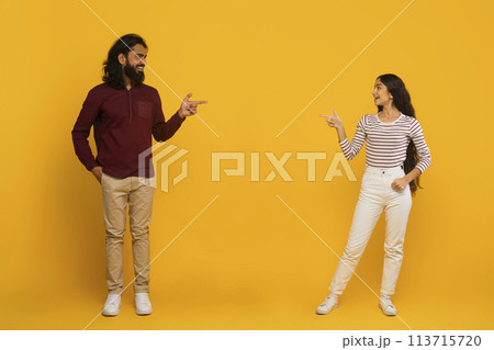 Man and woman pointing each other on yellow background Man and woman pointing each other on yellow background 113715720