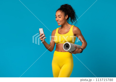 Woman checking phone holding a yoga mat 113715780